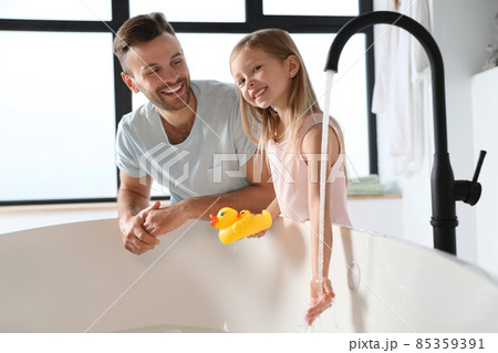 Father with his cute little daughter filling tub in bathroom 85359391