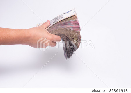 a thick wad of cash in his hand on a white background. a thick wad of cash in his hand on a white background. 85361913