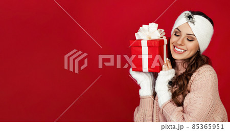 Happy woman holding a gift box. Portrait of happy smiling girl looking at delivered wrapped box Happy woman holding a gift box. Portrait of happy smiling girl looking at delivered wrapped box 85365951