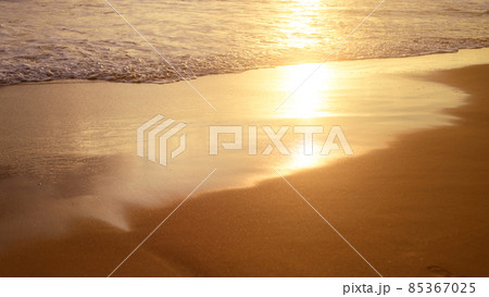 Sunset light shining on the ocean waves. Tropical sandy beach sunset reflection. 85367025