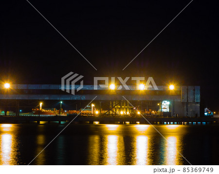 Night view of a seaport with a metal structure illuminated by bright lights Night view of a seaport with a metal structure illuminated by bright lights 85369749