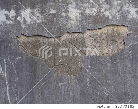 A wall with a fallen piece of gray plaster and a geometric pattern under it A wall with a fallen piece of gray plaster and a geometric pattern under it 85370185