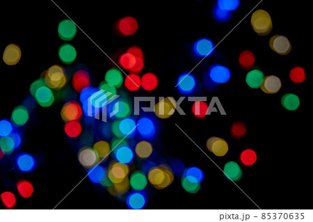 Defocused bokeh lights on black background, an abstract naturally blurred backdrop for Christmas eve or birthday party. Festive light texture. Colorful garland in blur. Overlay effect for design 85370635