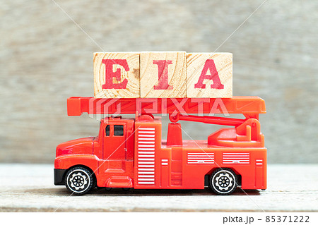 Fire ladder truck hold letter block in word EIA (abbreviation of Environmental Impact Assessment) on wood background 85371222