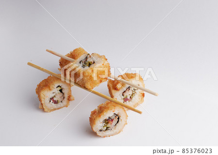 several rolls on the table, asian food, balance on chinese chopsticks, side view, sushi 85376023