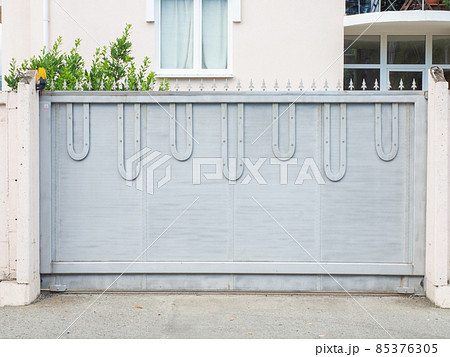 Blue-gray iron gates with sharp points on top are located in front of a lightcolored residential building Blue-gray iron gates with sharp points on top are located in front of a lightcolored residential building 85376305