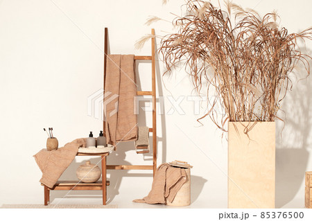 Natural waffle linen towels in earth tones on wood bench and towel ladder with bamboo toothbrushes, rattan baskets, and soap dispenser. Daily body care, spa and wellness zero waste bathroom concept Natural waffle linen towels in earth tones on wood bench and towel ladder with bamboo toothbrushes, rattan baskets, and soap dispenser. Daily body care, spa and wellness zero waste bathroom concept 85376500