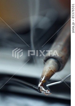 Wires being soldered together with a soldering iron. Melting solder wire on soldering iron tip 85376501