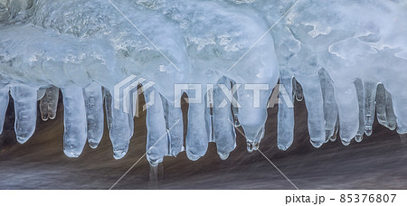 Icicles over the water in the river. Natural landscape. Winter. Background image. 85376807