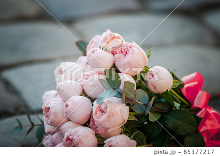 Gold wedding rings on the pink bouquet of flowers 85377217