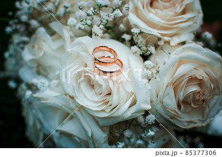 Gold wedding rings lying on the white bouquet of flowers Gold wedding rings lying on the white bouquet of flowers 85377306