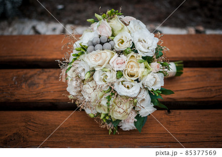 white bouquet of flowers lies on a brown bench white bouquet of flowers lies on a brown bench 85377569