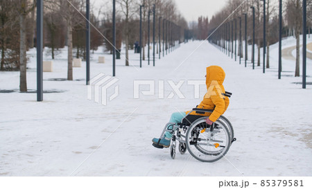 Disabled woman in a wheelchair outdoors in winter. Disabled woman in a wheelchair outdoors in winter. 85379581