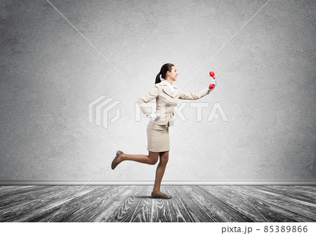 Woman running in room with vintage red phone Woman running in room with vintage red phone 85389866