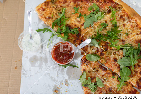 Unfinished pizza with arugula leaves at a college party. Unfinished pizza with arugula leaves at a college party. 85390286