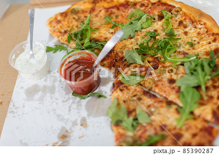 Unfinished pizza with arugula leaves at a college party. Unfinished pizza with arugula leaves at a college party. 85390287