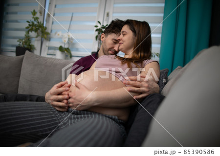 The husband closes his eyes and hugs his head to his wife's temple. A married couple hugs each other. Pregnant woman. The husband closes his eyes and hugs his head to his wife's temple. A married couple hugs each other. Pregnant woman. 85390586