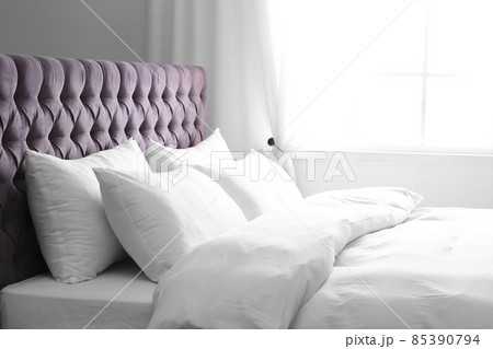 Modern bed with soft pillows near window 85390794