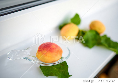 Apricots and their leaves lie on a white windowsill. Selective focus 85391237