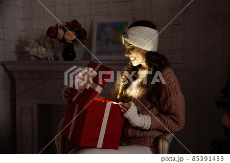 Happy young woman with a present, opening a Christmas present box. Portrait of happy smiling girl Happy young woman with a present, opening a Christmas present box. Portrait of happy smiling girl 85391433