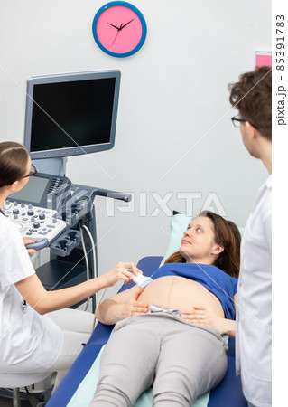 A nurse performs an ultrasound on a pregnant patient under the guidance of the attending doctor. A nurse performs an ultrasound on a pregnant patient under the guidance of the attending doctor. 85391783