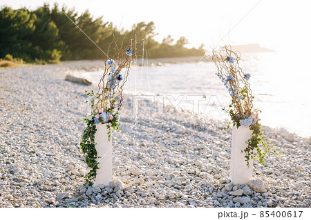 Wedding semi-arch with floral decor on a pebble beach Wedding semi-arch with floral decor on a pebble beach 85400617