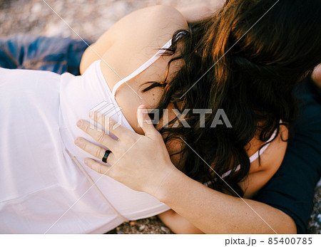 Man and woman hugging while lying on the gravel path in the park Man and woman hugging while lying on the gravel path in the park 85400785