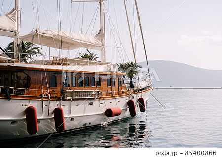 Beautiful sailing yacht with folded sails stands in the bay at the pier Beautiful sailing yacht with folded sails stands in the bay at the pier 85400866