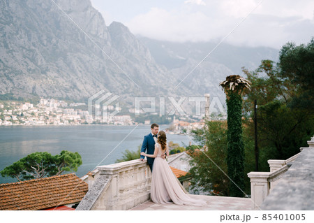 Bride hugs groom on the stone terrace against the backdrop of the bay Bride hugs groom on the stone terrace against the backdrop of the bay 85401005