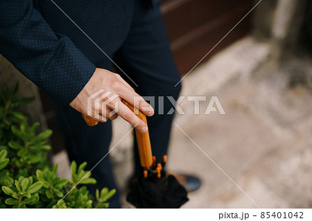 Man hand rests on the wooden cane of the umbrella. Close-up 85401042