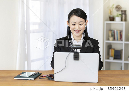 イヤホンをつけてウェブカメラに向かって話す若い女性　就活　オンライン面接イメージ 85401243