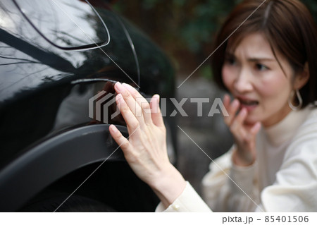 車の傷を確認する女性 85401506