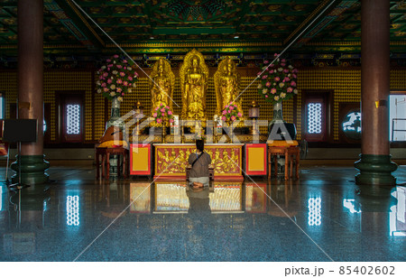 A women sitting praying pay respect to Buddha statue in the Wat Borom Racha Kanchana Phi Sek Anuson. A women sitting praying pay respect to Buddha statue in the Wat Borom Racha Kanchana Phi Sek Anuson. 85402602
