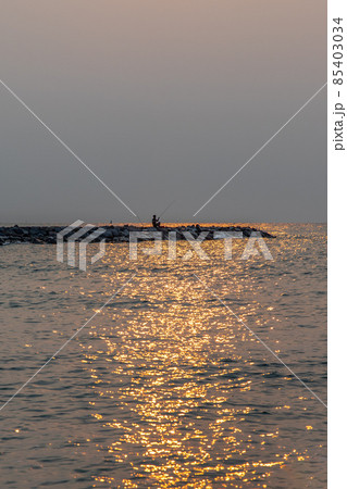 Angler with fishing rod on at the Calm beach in the morning. Angler with fishing rod on at the Calm beach in the morning. 85403034