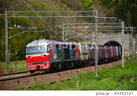 色とりどりのコンテナを牽き春の暖かな陽射しを浴びて走る貨物列車 85403547