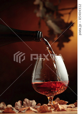 Cognac is poured into a glass from a bottle. 85404312