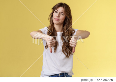 Honestly very bad. Disappointed upset curly-haired girl tilt head smirk displeased disagree show thumbs down sign dislike unimpressed awful idea stand yellow background uninterested Honestly very bad. Disappointed upset curly-haired girl tilt head smirk displeased disagree show thumbs down sign dislike unimpressed awful idea stand yellow background uninterested 85408770