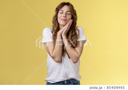 Happy relieved carefree charming european woman curly long hair close eyes smiling joyfully daydreaming imaging positive moments recall nice memory hold palms near face sleepy nap attitude Happy relieved carefree charming european woman curly long hair close eyes smiling joyfully daydreaming imaging positive moments recall nice memory hold palms near face sleepy nap attitude 85409493