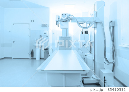 X-ray department in modern hospital. Radiology room with scan machine with empty bed. Technician adjusting an x-ray machine. Scanning chest, heart, lungs in modern clinic office. 85410552