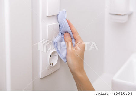 Cleaning switches and sockets with a microfiber cloth. Woman hand using wet wipe for cleaning home room door link. Sanitize surfaces prevention in hospital and public spaces against corona virus. Cleaning switches and sockets with a microfiber cloth. Woman hand using wet wipe for cleaning home room door link. Sanitize surfaces prevention in hospital and public spaces against corona virus. 85410553