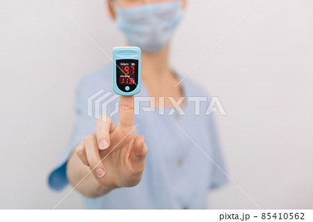 Pulse oximeter with hand of doctor isolated on white. The concept of portable digital device to measure person's oxygen saturation. Measuring oxygen saturation, pulse rate and oxygen levels Pulse oximeter with hand of doctor isolated on white. The concept of portable digital device to measure person's oxygen saturation. Measuring oxygen saturation, pulse rate and oxygen levels 85410562