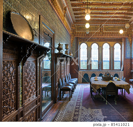 Manial Palace of Prince Mohammed Ali. Dining room at the Residence Building, with ornate wall and ceiling, Big ornate window, built-in wooden decorated cupboards and ornate carpet, Cairo, Egypt Manial Palace of Prince Mohammed Ali. Dining room at the Residence Building, with ornate wall and ceiling, Big ornate window, built-in wooden decorated cupboards and ornate carpet, Cairo, Egypt 85411021