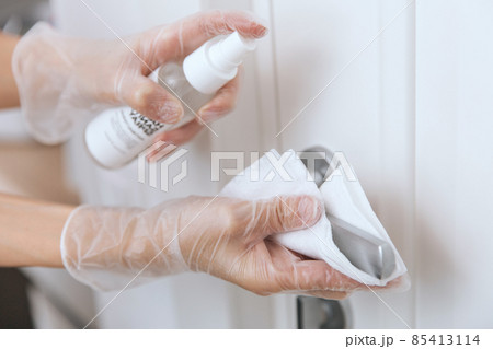 Cleaning door handles with wet wipe and white gloves. Sanitize surfaces prevention in hospital and public spaces against corona virus. Woman hand using towel for cleaning home room door link. Cleaning door handles with wet wipe and white gloves. Sanitize surfaces prevention in hospital and public spaces against corona virus. Woman hand using towel for cleaning home room door link. 85413114
