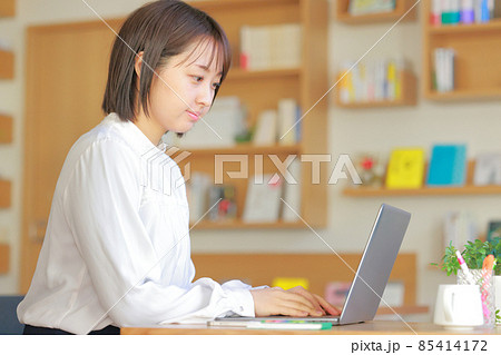 大きな本棚のあるオフィスでデスクワークする女性1 85414172
