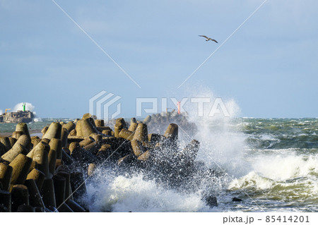 during stormy weather, large waves crash against the concrete blocks of a breakwater 85414201