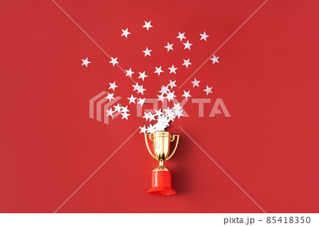 Stars fly out of the gold-colored victory cup on red background 85418350