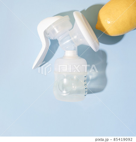 Manual breast pump with lemon on blue background with hard shadows 85419092