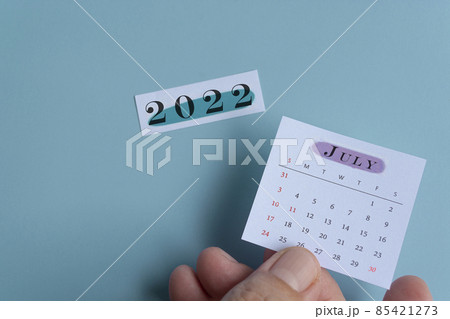 Hand holding a white July calendar with green background of notepad year 2022 Hand holding a white July calendar with green background of notepad year 2022 85421273