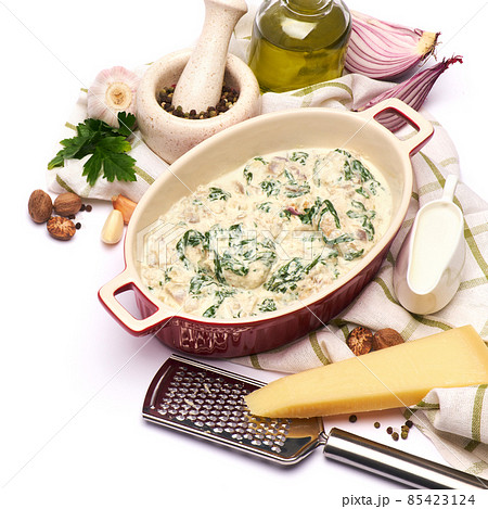 Delicious meatballs with spinach in a creamy sauce in baking dish on white background 85423124