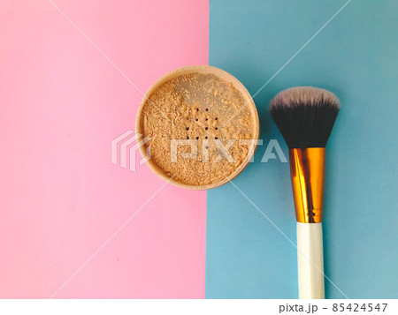 loose powder on a bright background. next to a powder makeup brush. powder brush, fluffy, made of natural material. brush with white handle with gold tip 85424547
